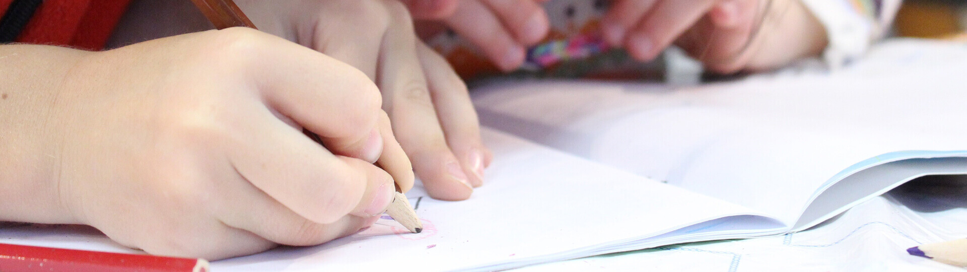 Kinderhand mit Stift und Schulheft